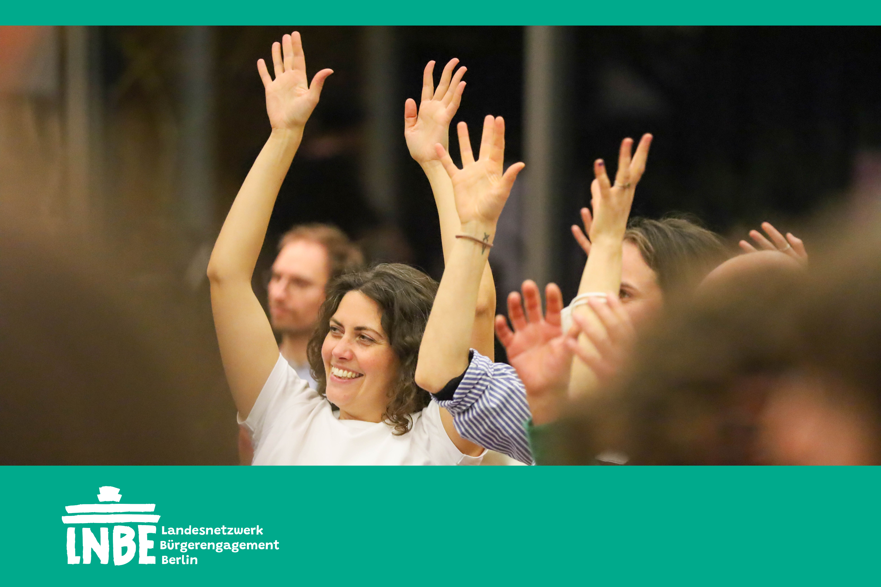 Teilnehmer:innen halten die Hände bei einer Konferenz in die Höhe.