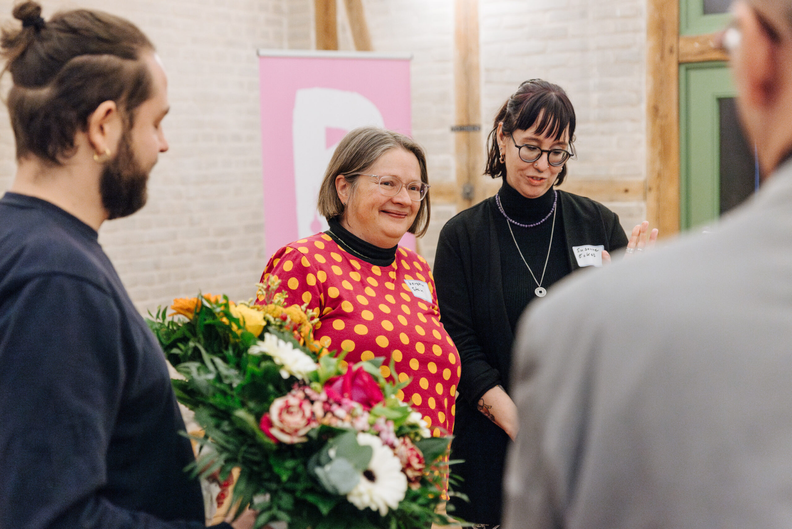 Zwei Frauen erhalten auf einer Veranstaltung einen Blumenstrauß.